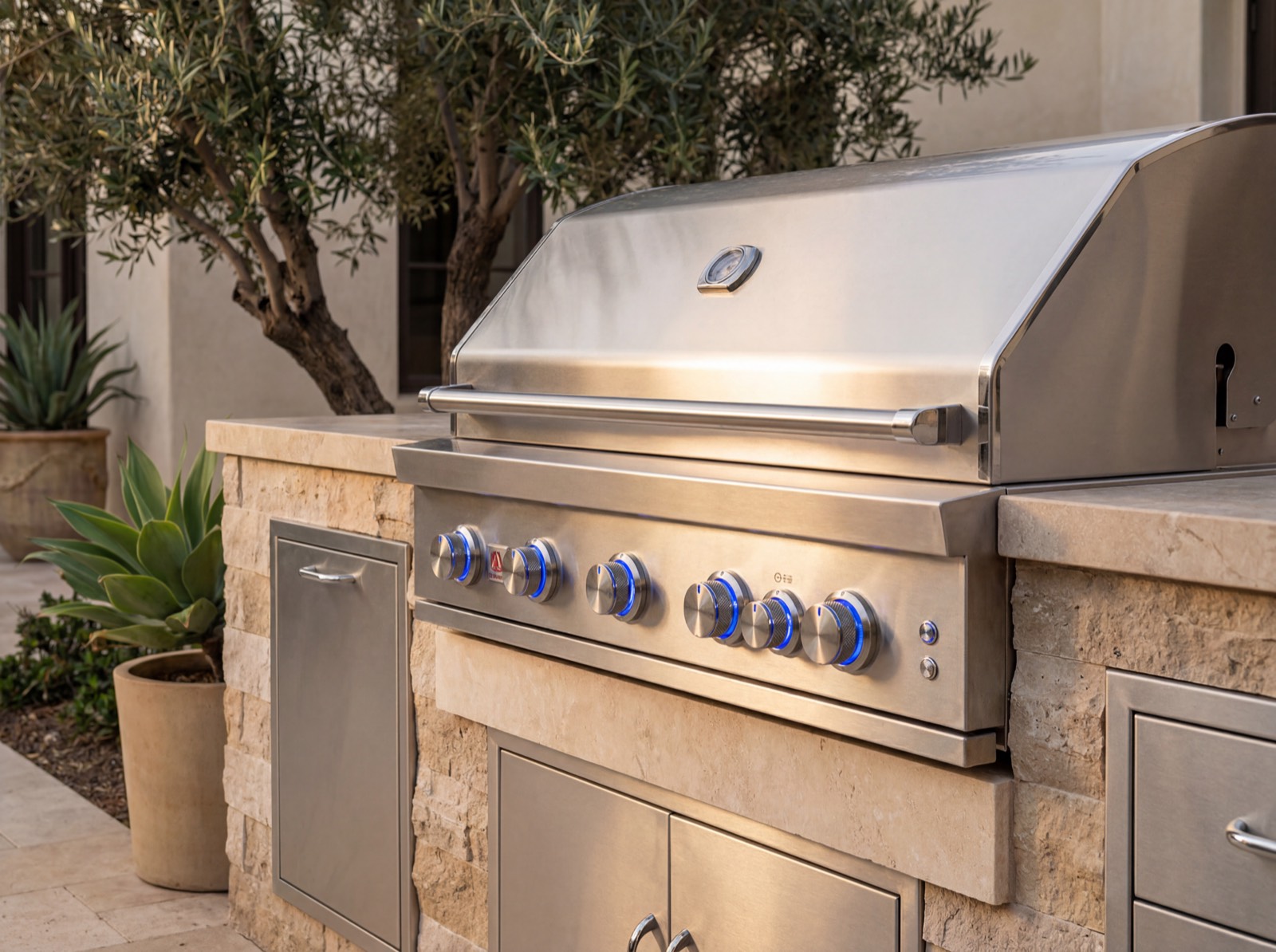 Summerset Sizzler Pro grill set in a stacked-stone and travertine outdoor kitchen island with olive trees — Rancho Santa Fe, San Diego